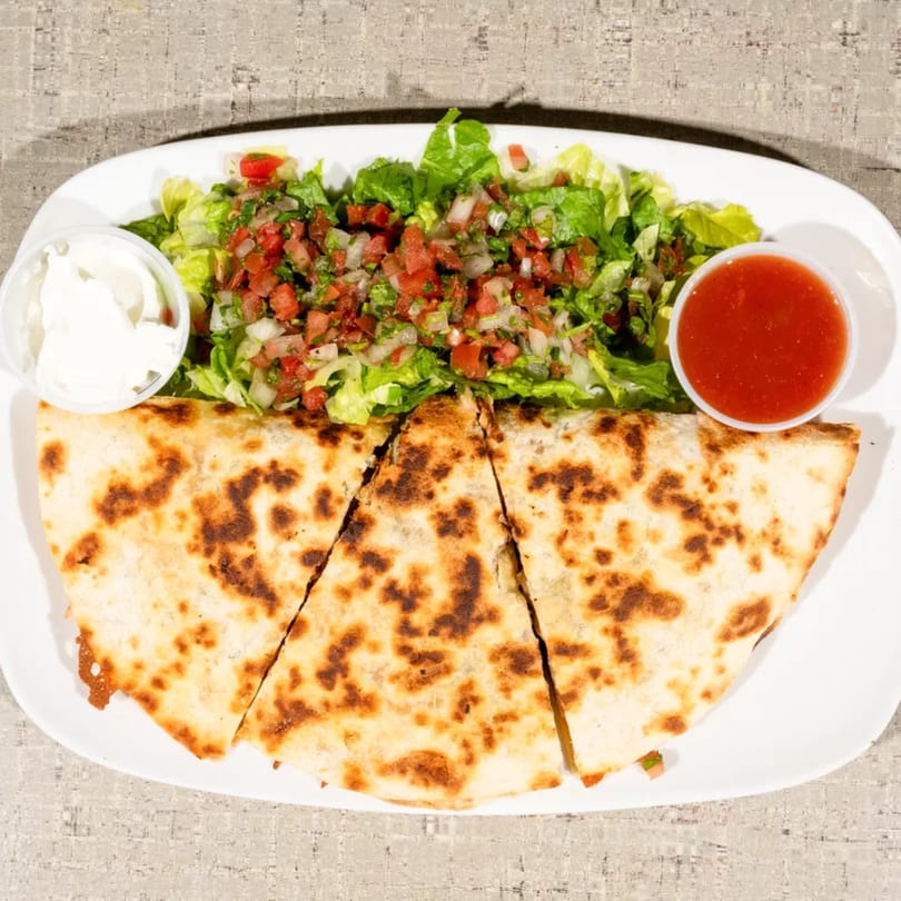 Three quesadilla slices with a side of lettuce, pico de gallo, sour cream, and salsa.